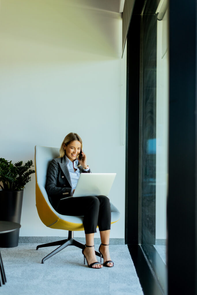 businesswoman modern office talking phone using laptop daytime