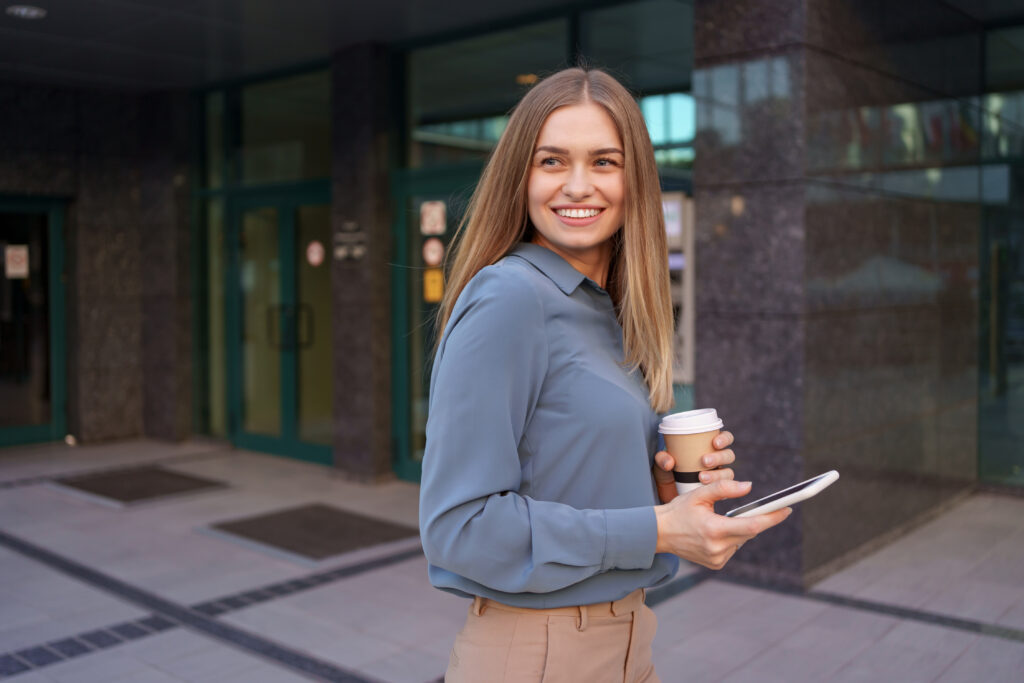 belle jeune femme utilise une application sur son smartphone pour envoyer un message texte a proximite des batiments commerciaux