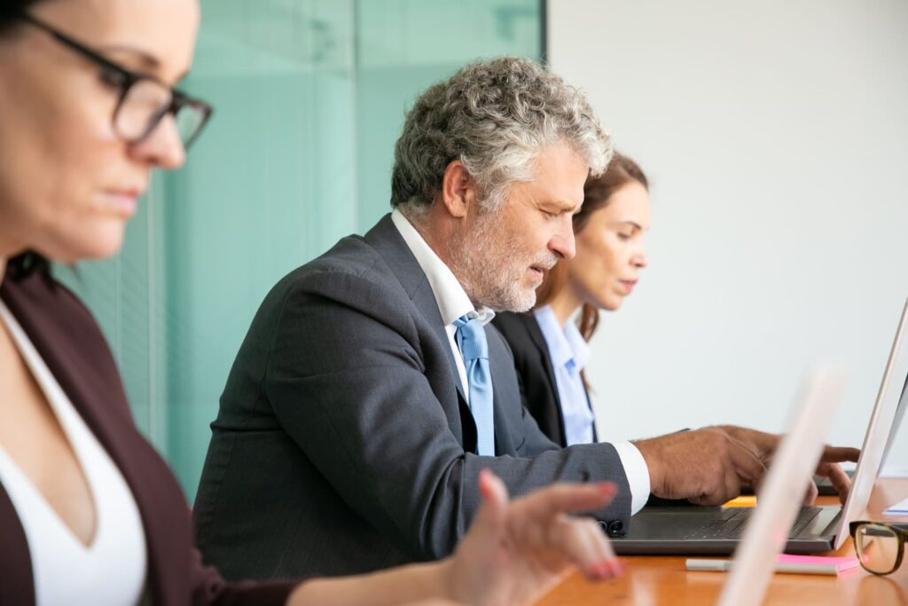 Trois professionnels en réunion, travaillant ensemble sur des ordinateurs dans un environnement professionnel