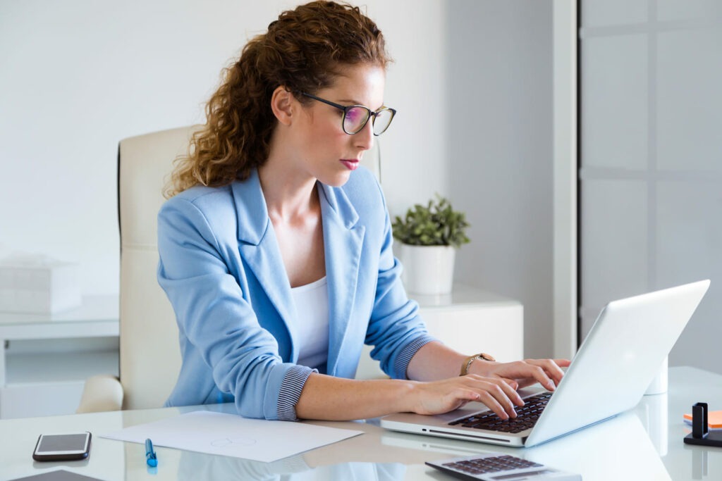 Femme travaillant sur un ordinateur portable dans un environnement professionnel, illustrant la formation et l’apprentissage en ligne.