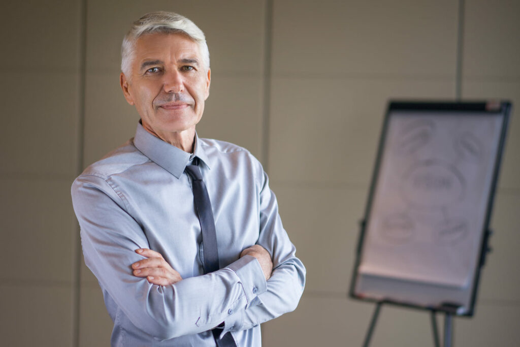 1. Directeur du développement expérimenté, en tenue professionnelle, posant dans un bureau devant un tableau de présentation.