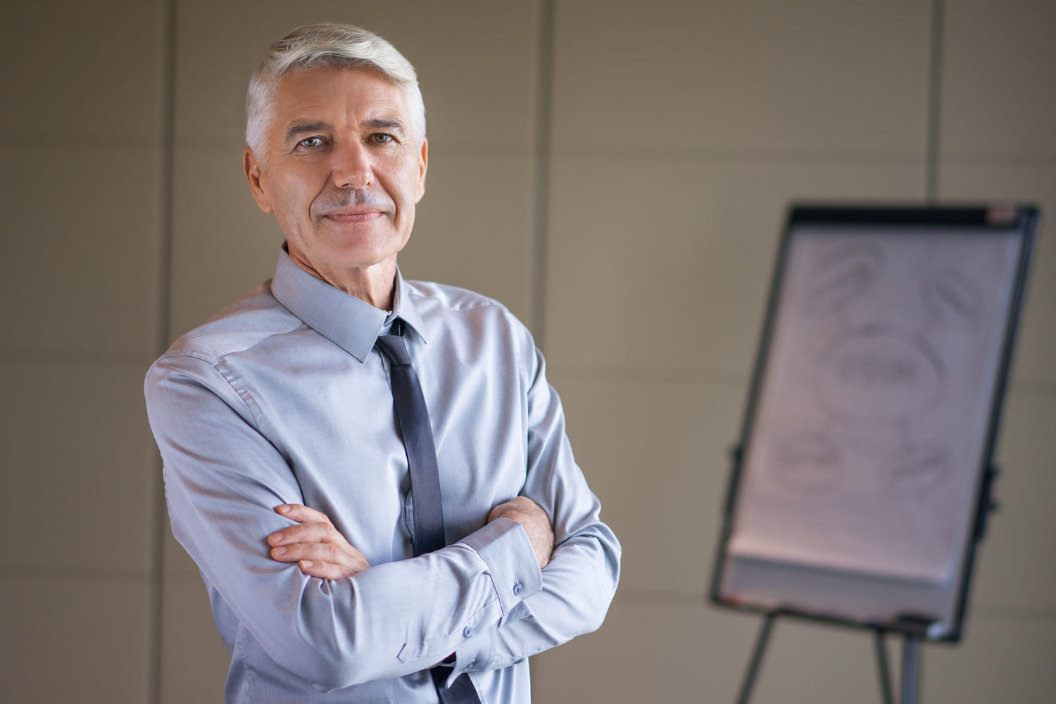 1. Directeur du développement expérimenté, en tenue professionnelle, posant dans un bureau devant un tableau de présentation.