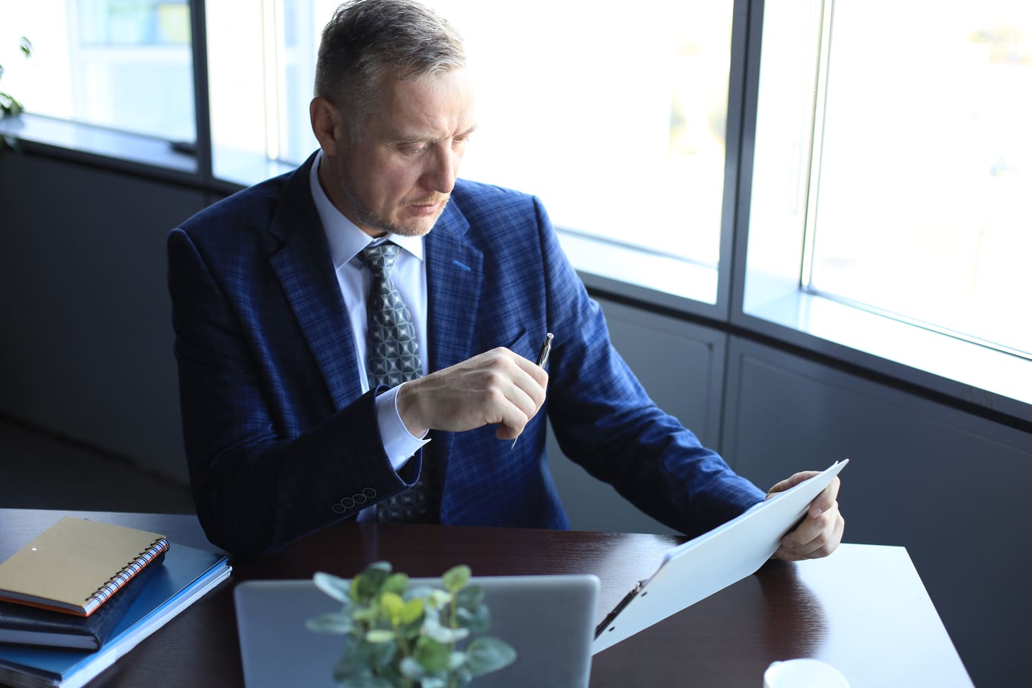 1. Gestionnaire de fortune en costume étudiant des documents financiers à son bureau.