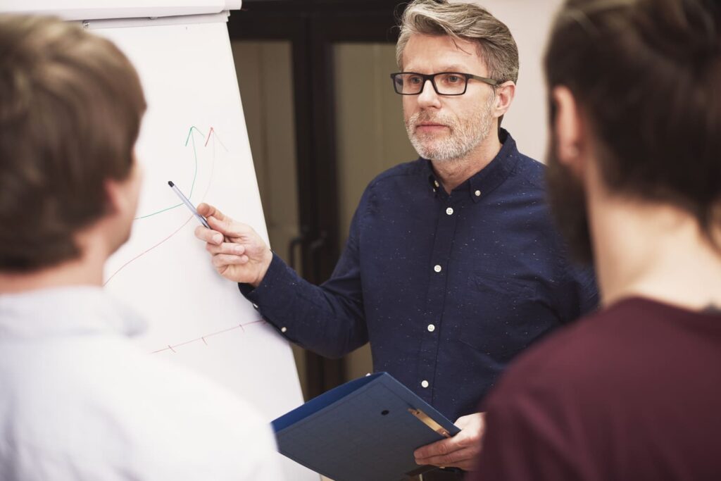 Directeur de réseau présentant des graphiques à ses collaborateurs lors d’une réunion professionnelle.