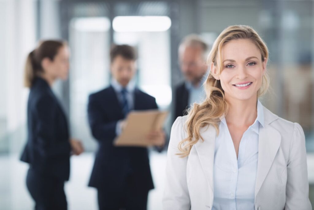 Directrice du développement en entreprise, souriante et professionnelle, devant une équipe de collaborateurs en réunion.