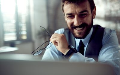 Young happy businessman working on a computer in the office.