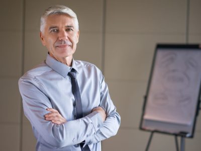 1. Directeur du développement expérimenté, en tenue professionnelle, posant dans un bureau devant un tableau de présentation.