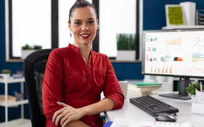 Portrait of business woman in corporate office sitting at desk smiling at camera. Company executive leadership working on financial statistics. worker doing charts on computer.